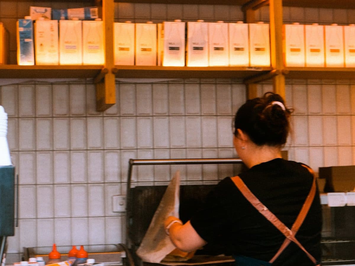 Staff bagging an order behind a takeaway counter under a Pick Up sign