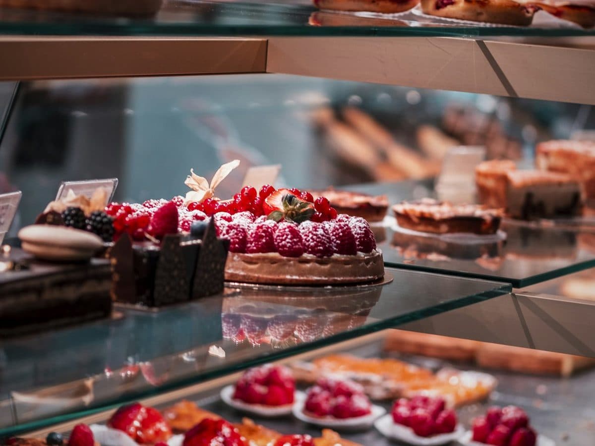 A patisserie display case of fruit tarts and cake slices