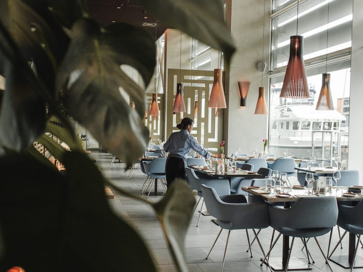 A server laying up tables in a bright dining room before service